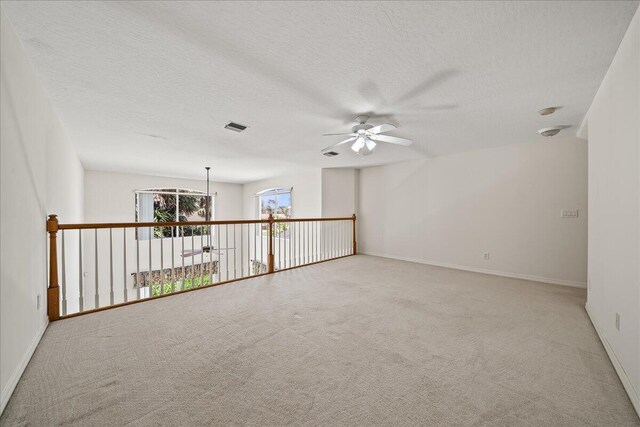 carpeted empty room with ceiling fan and a textured ceiling