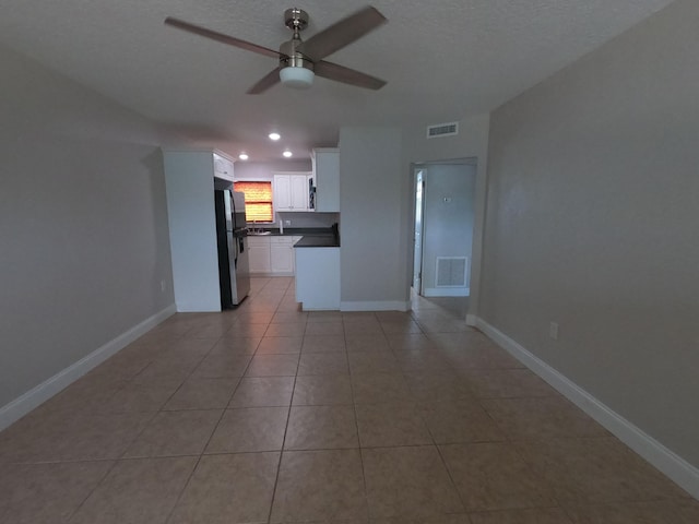 unfurnished living room featuring tile floors and ceiling fan