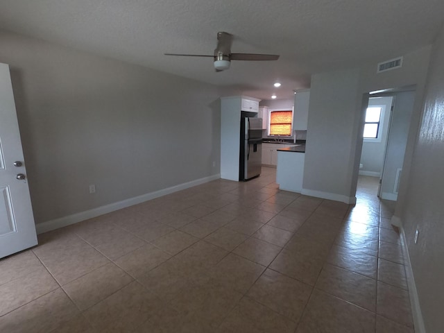 unfurnished living room with ceiling fan and light tile flooring