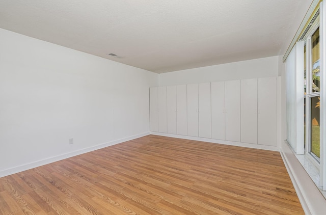 spare room featuring a textured ceiling and light wood-type flooring