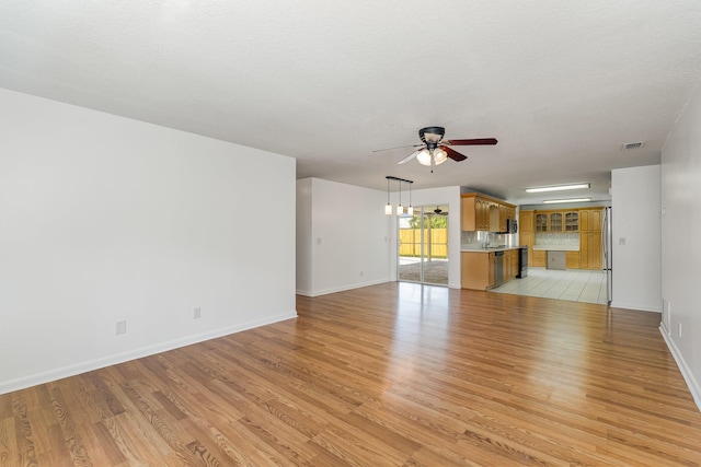 unfurnished living room featuring ceiling fan, light hardwood / wood-style flooring, a textured ceiling, and sink