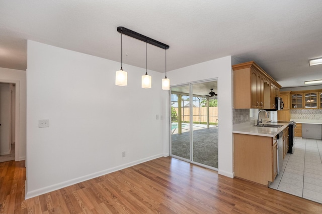 kitchen featuring light hardwood / wood-style floors, hanging light fixtures, a textured ceiling, sink, and tasteful backsplash