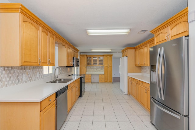 kitchen with sink, appliances with stainless steel finishes, light tile patterned flooring, and decorative backsplash