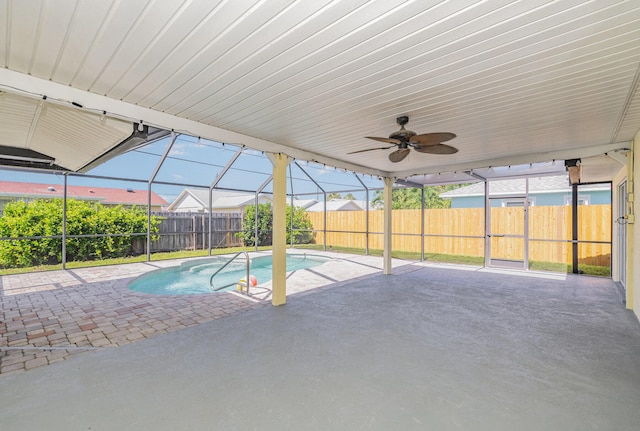 view of swimming pool with ceiling fan, a patio, and glass enclosure