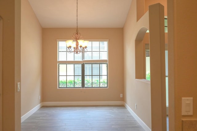 unfurnished dining area with a chandelier, plenty of natural light, and hardwood / wood-style flooring