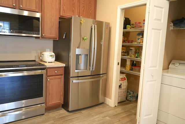 kitchen featuring washer / clothes dryer, light hardwood / wood-style flooring, and appliances with stainless steel finishes