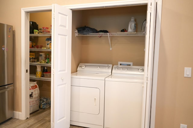 laundry room with washer and dryer and light wood-type flooring