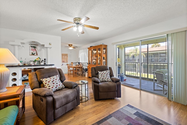 living room featuring a textured ceiling, hardwood / wood-style flooring, and ceiling fan