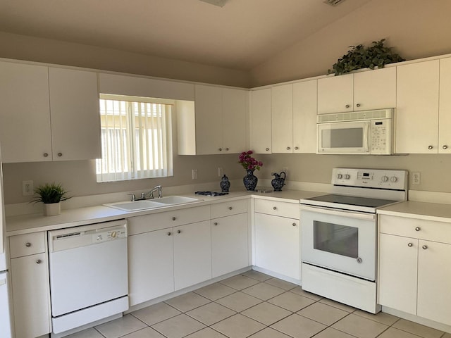 kitchen featuring lofted ceiling, white appliances, white cabinets, sink, and light tile patterned floors