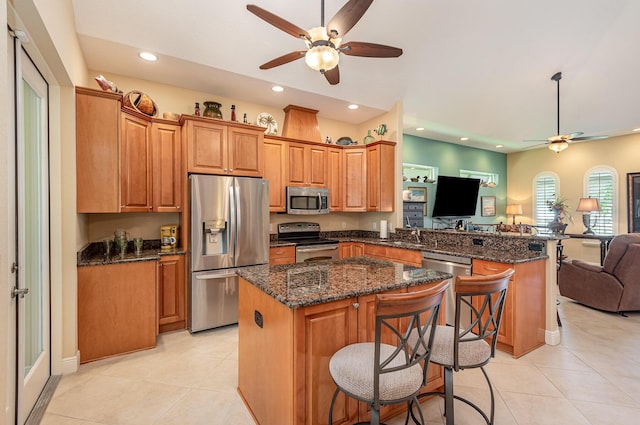 kitchen featuring a kitchen breakfast bar, a kitchen island, dark stone countertops, and stainless steel appliances