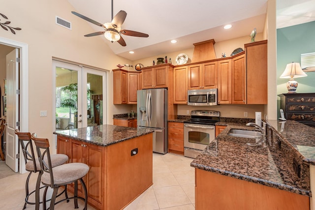 kitchen featuring kitchen peninsula, french doors, stainless steel appliances, vaulted ceiling, and sink