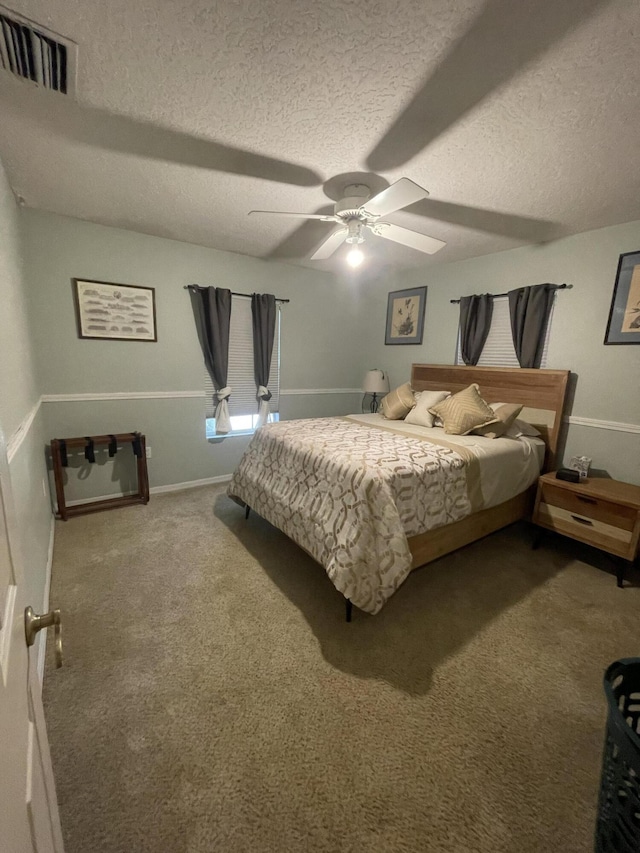 carpeted bedroom featuring ceiling fan and a textured ceiling