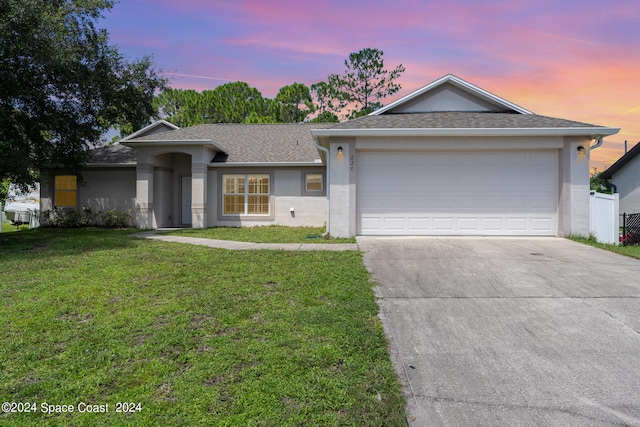 ranch-style house featuring a garage and a yard