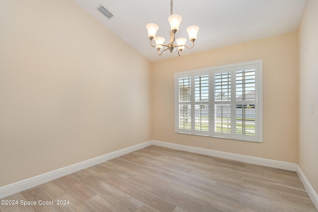 empty room with a notable chandelier, light wood-type flooring, and vaulted ceiling