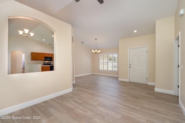 interior space with ceiling fan with notable chandelier, light wood-type flooring, and vaulted ceiling