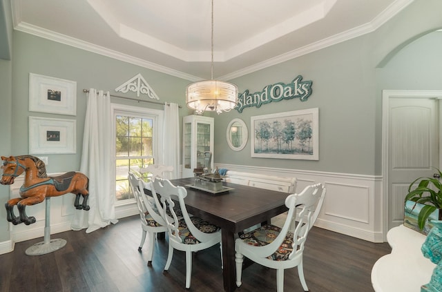 dining room with ornamental molding, a tray ceiling, a chandelier, and dark wood-type flooring