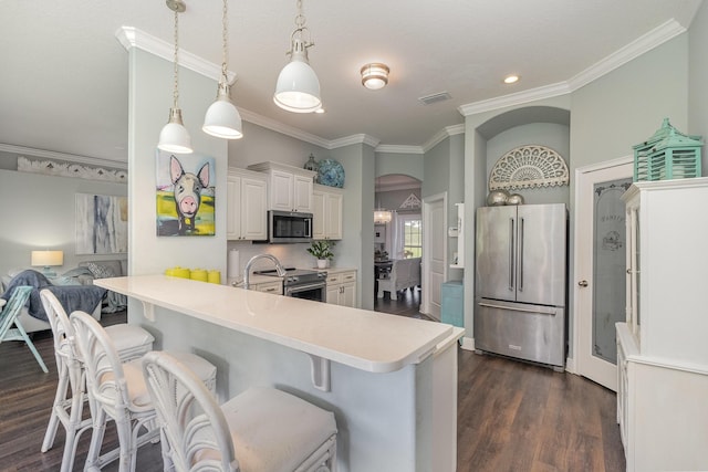 kitchen with stainless steel appliances, dark wood-type flooring, ornamental molding, a breakfast bar, and white cabinetry