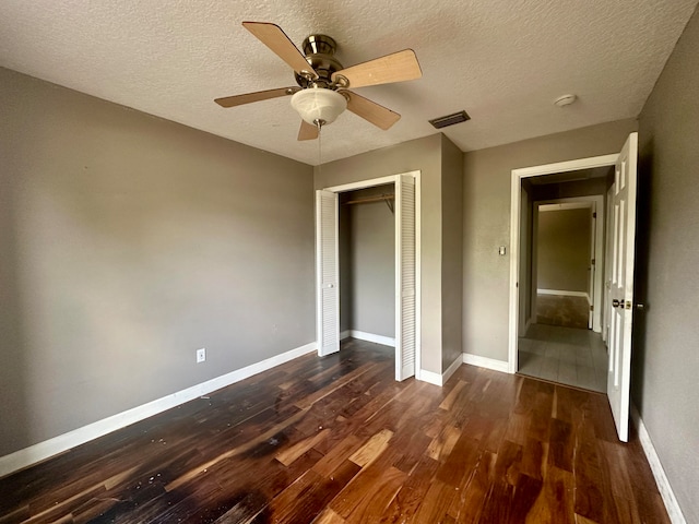 unfurnished bedroom featuring a textured ceiling, a closet, ceiling fan, and dark hardwood / wood-style floors