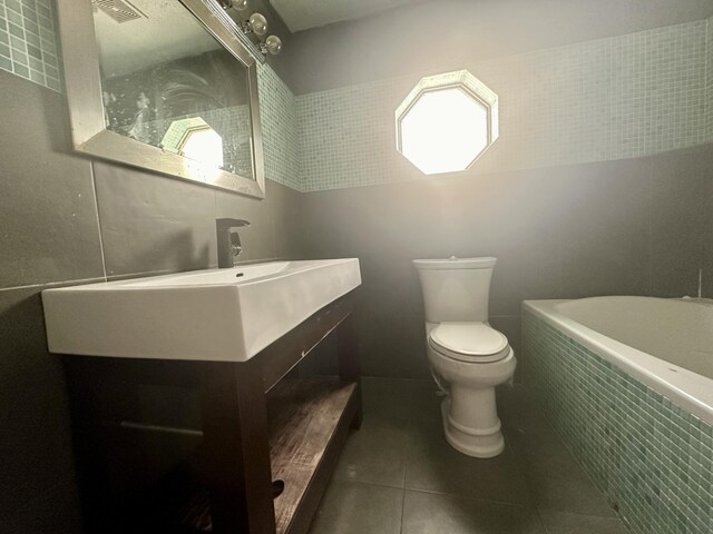 bathroom with tile flooring, vanity, toilet, and tile walls