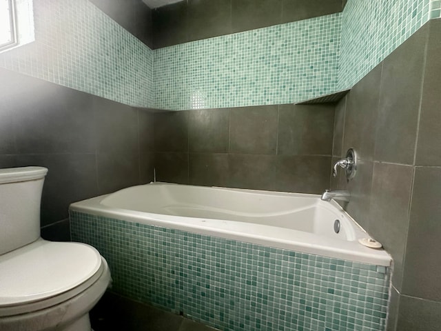 bathroom with tile walls, tiled shower / bath, and toilet