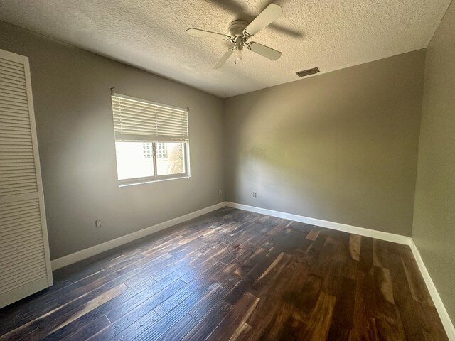 unfurnished room featuring ceiling fan, a textured ceiling, and dark wood-type flooring