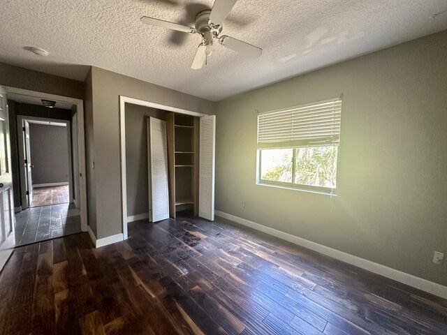 unfurnished bedroom with a textured ceiling, a closet, ceiling fan, and dark hardwood / wood-style floors