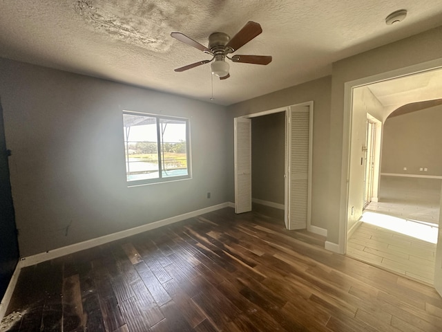 unfurnished bedroom with ceiling fan, a closet, hardwood / wood-style flooring, and a textured ceiling