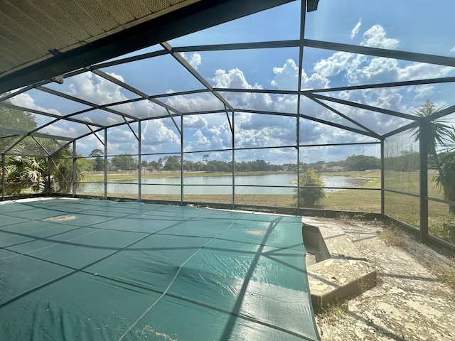 view of swimming pool featuring glass enclosure and a water view