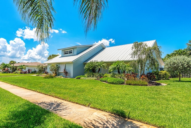 view of front facade with metal roof, a front lawn, a standing seam roof, and stucco siding