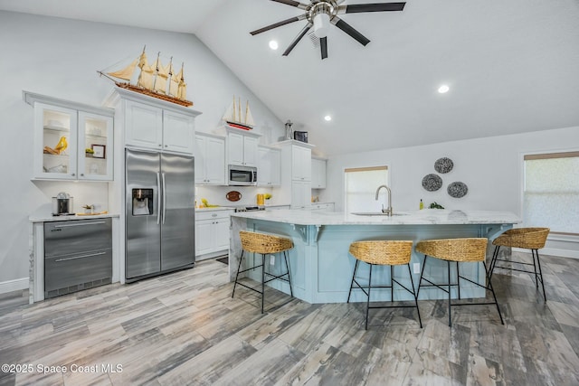 kitchen featuring appliances with stainless steel finishes, white cabinetry, a sink, a large island with sink, and a kitchen breakfast bar