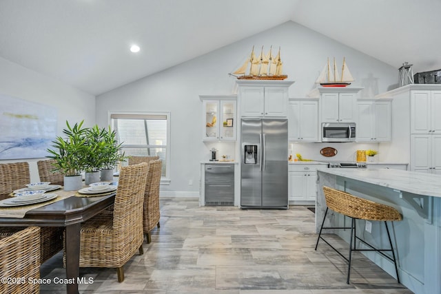 kitchen featuring white cabinetry, stainless steel appliances, light stone counters, and a kitchen breakfast bar