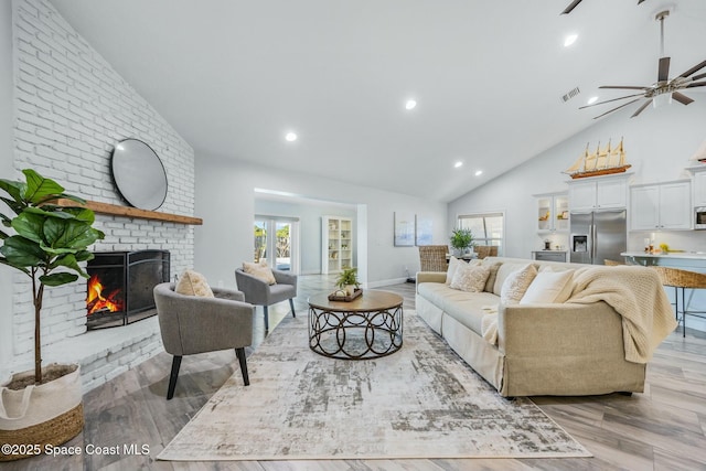 living room with light wood-type flooring, a wealth of natural light, a brick fireplace, and visible vents