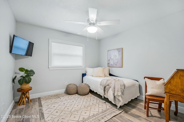 bedroom with a ceiling fan, baseboards, and wood finished floors