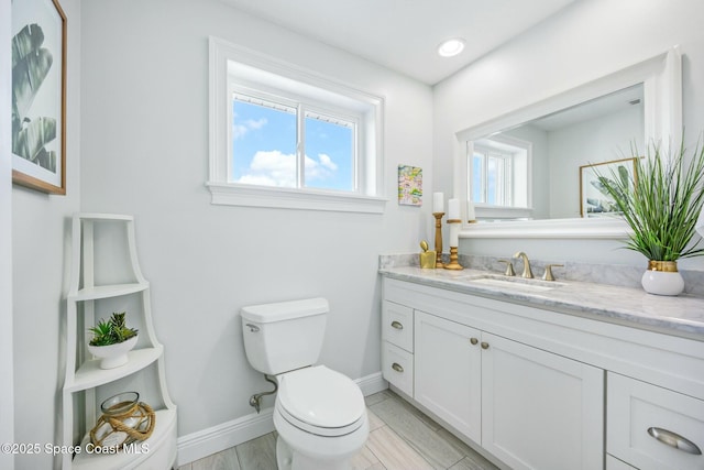 half bath with recessed lighting, vanity, toilet, and baseboards