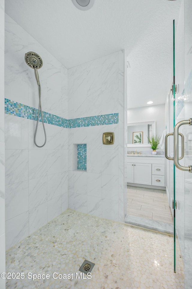 full bath with a stall shower, vanity, and a textured ceiling