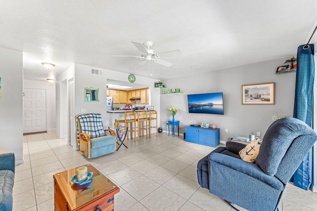 living room featuring ceiling fan, light tile patterned floors, and a textured ceiling