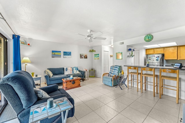 living room with ceiling fan, light tile patterned floors, and a textured ceiling