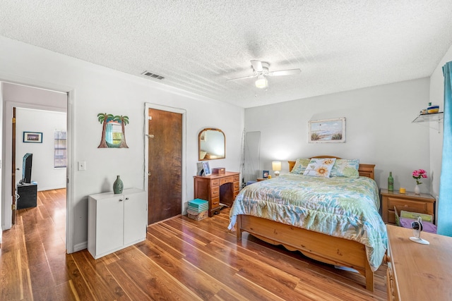 bedroom with hardwood / wood-style flooring, ceiling fan, and a textured ceiling