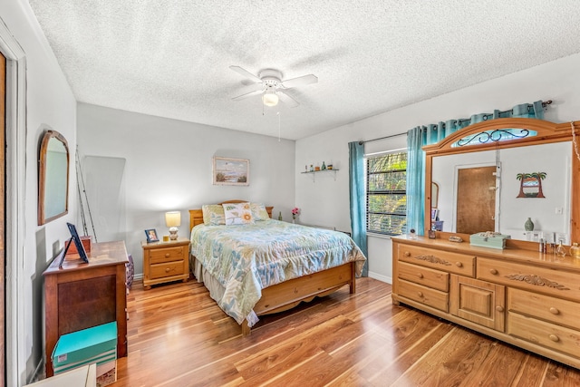 bedroom with ceiling fan, light wood-type flooring, and a textured ceiling