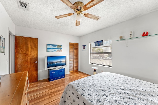 bedroom featuring ceiling fan, a textured ceiling, and light wood-type flooring