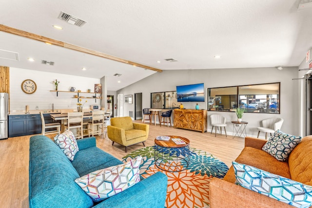 living room with vaulted ceiling with beams, light wood-type flooring, a textured ceiling, and sink