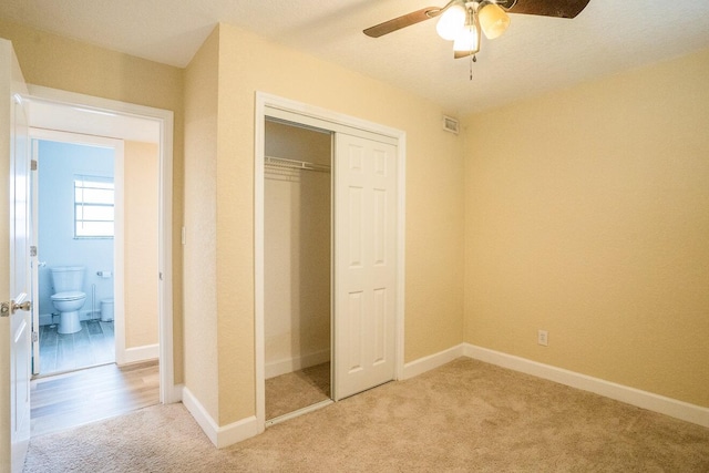 unfurnished bedroom featuring light colored carpet, a closet, and ceiling fan