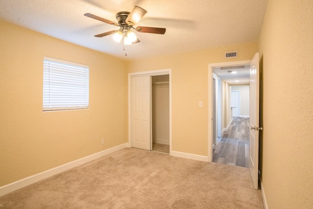 unfurnished bedroom featuring ceiling fan, a closet, and light colored carpet