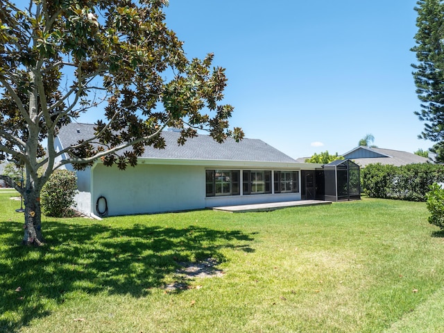 rear view of property featuring a lawn and stucco siding