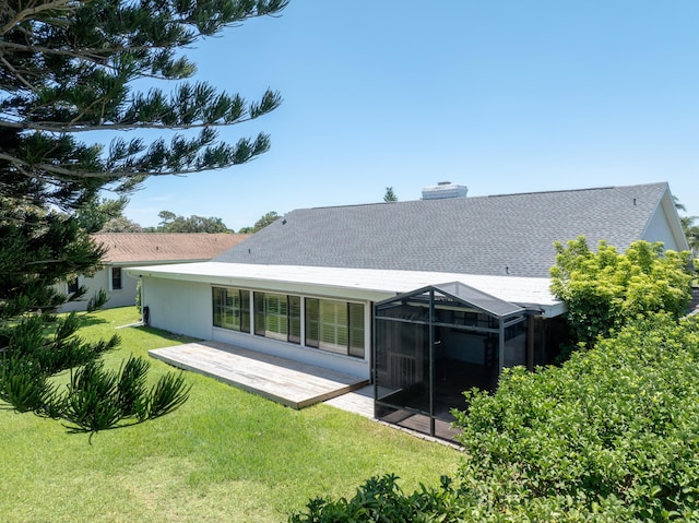 back of house featuring a lanai, a patio area, a lawn, and a chimney