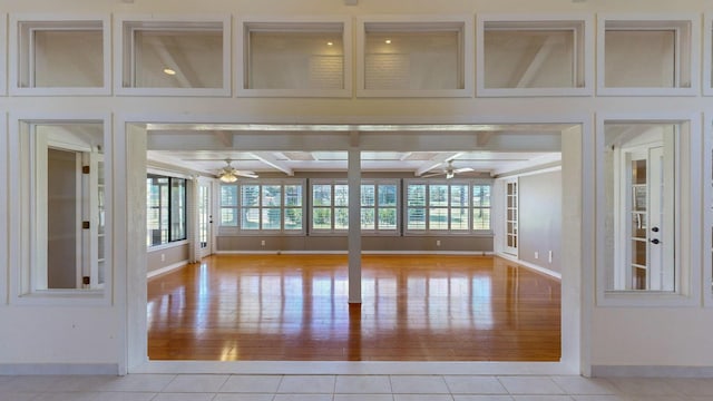 tiled spare room featuring beamed ceiling and ceiling fan