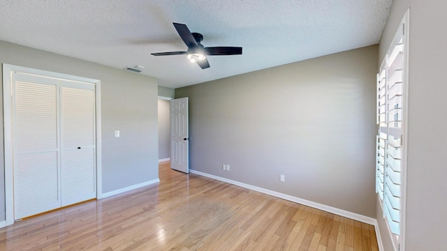 unfurnished bedroom with light hardwood / wood-style flooring, a textured ceiling, ceiling fan, and a closet