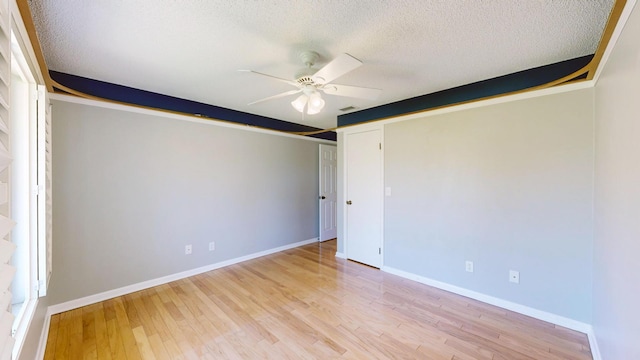 unfurnished room with baseboards, ceiling fan, a textured ceiling, and light wood finished floors