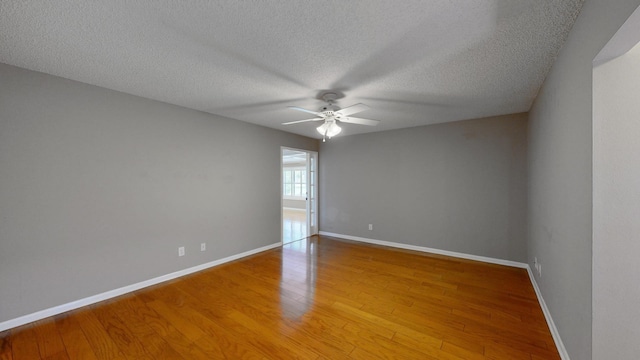 empty room with ceiling fan, wood-type flooring, and a textured ceiling