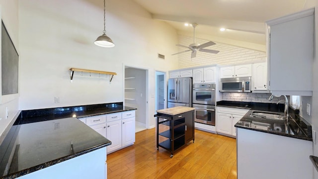 kitchen with sink, appliances with stainless steel finishes, pendant lighting, ceiling fan, and white cabinets